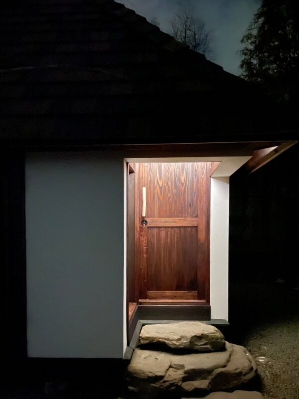 古材と漆喰壁を使った小屋の夜の木製玄関と石段